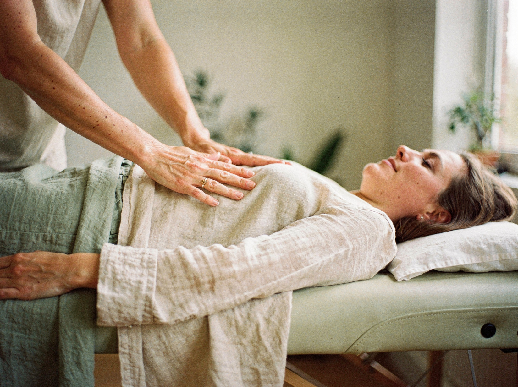 Reiki practitioner's hands resting gently over a person lying peacefully on a treatment table